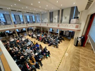 Foto des Saales mit Redner Prof. Rohe und Zuhörern