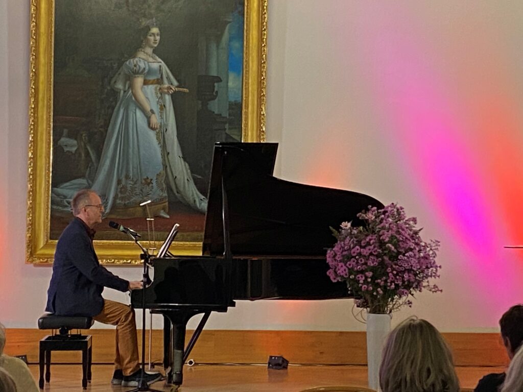 Prof. Bubmann bei seiner Präsentation singend am Klavier.